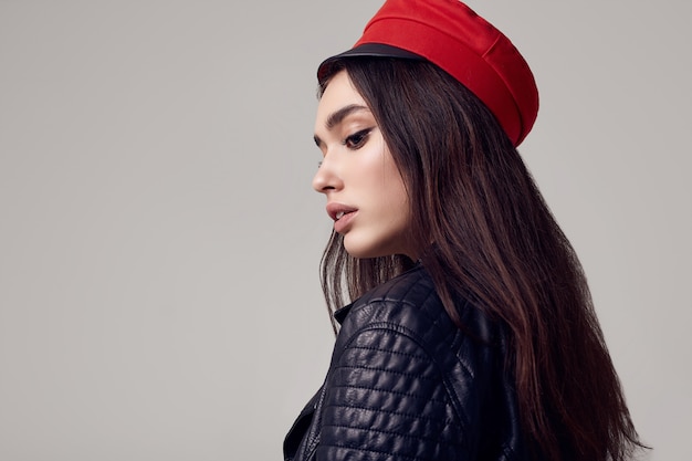 Fashion brunette woman wearing a leather jacket and red hat