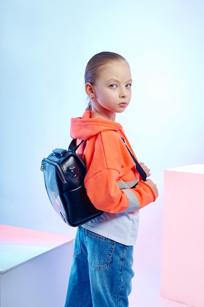 Fashion children pose with a collection of bags and clutches. Bright girl clothes.