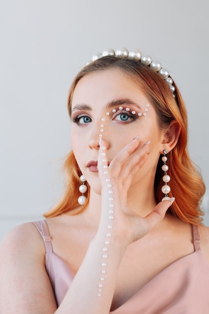 Fashion closeup portrait of a young womans face with makeup made of motherofpearl beads in the form ...