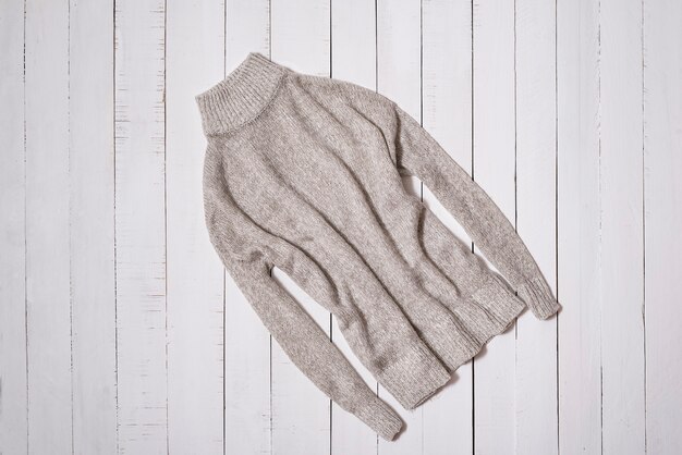 Fashion clothes. Gray knitted sweater on white wooden floor planks