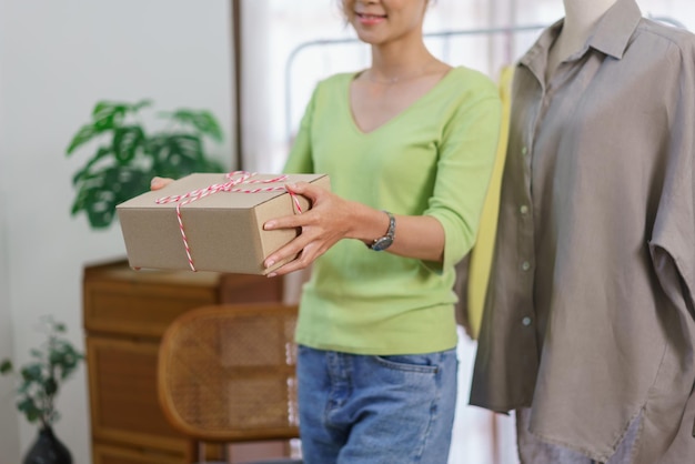 Concetto di commerciante di vestiti di moda designer femminile tiene la scatola dei pacchi e si prepara alla spedizione al cliente