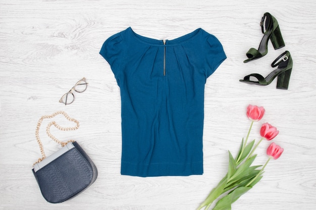 Fashion concept. Blue blouse, handbag, glasses, black shoes and pink tulips. Top view
