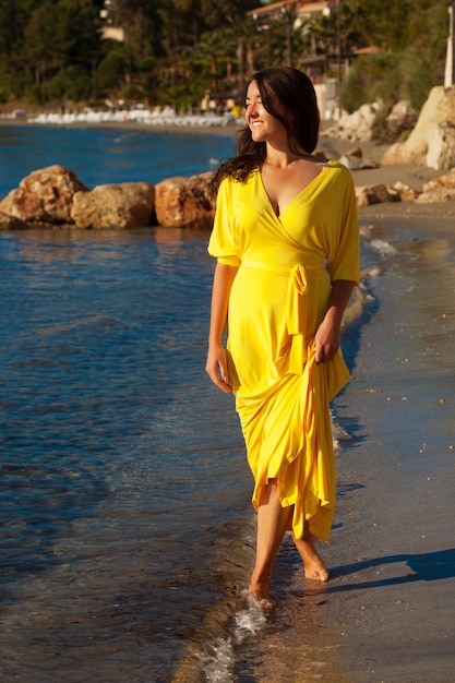 Fashion concept Woman with long yellow dress walking alone on the beach