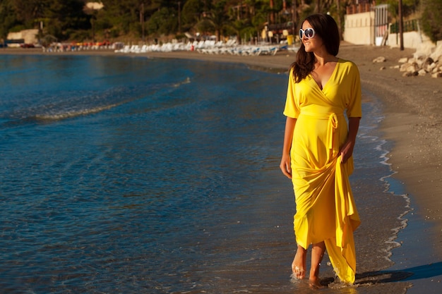 Fashion concept Woman with long yellow dress walking alone on the beach