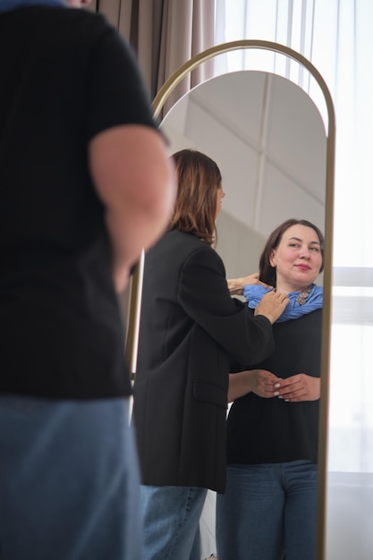 fashion consultation a stylist skillfully adjusts a blue scarf on a client while adding a bold necklace this photo highlights the personalized and attentive nature of fashion styling services
