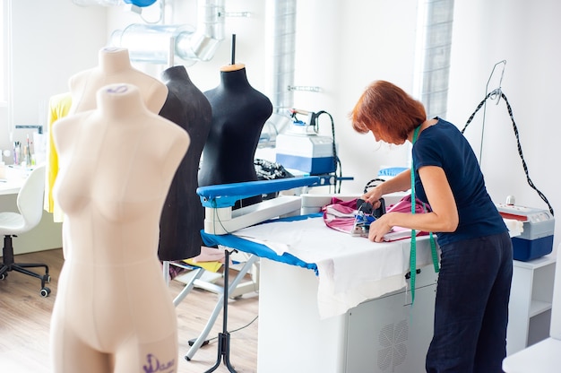 Photo fashion design studio hanging clothes sewing machine and various sewing related items on the table