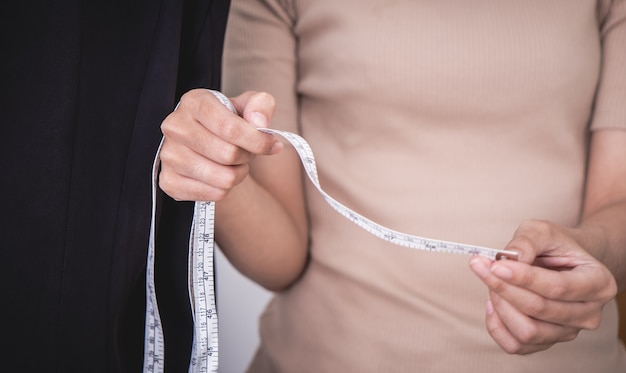 Fashion Designer hand is measuring clothes with measuring tape