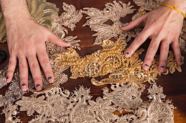 Fashion designer hands with silk lace fabric, decorating with embroidery.