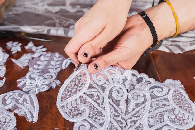 Fashion designer hands with silk lace fabric, decorating with embroidery.