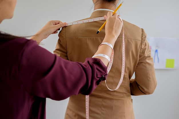 Foto designer di moda che misura una donna in studio