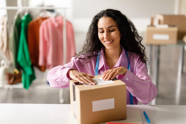 Fashion designer packaging garments preparing for delivery in clothing showroom