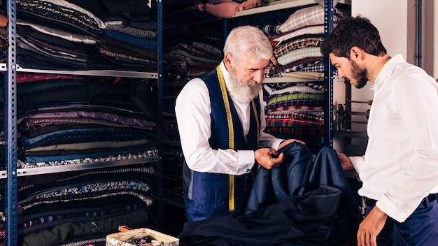 Fashion designer showing fabric to his customer in the shop