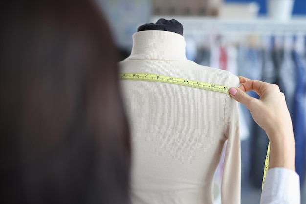 Fashion designer stylist takes measurements with centimeter from clothes on mannequin