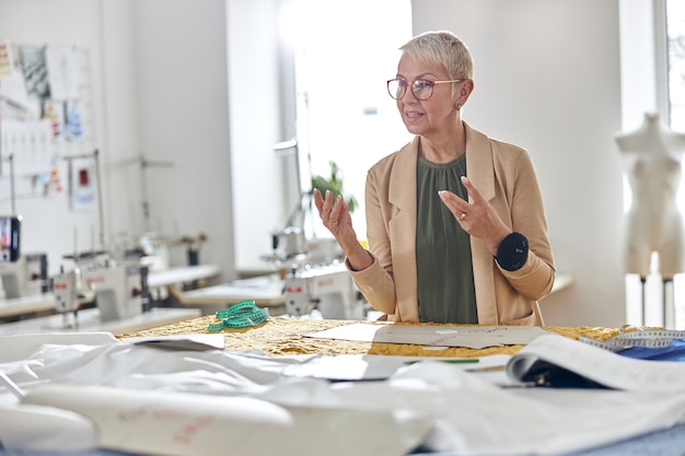 Fashion designer with glasses and pin pillow in wrist shoots video in light workshop