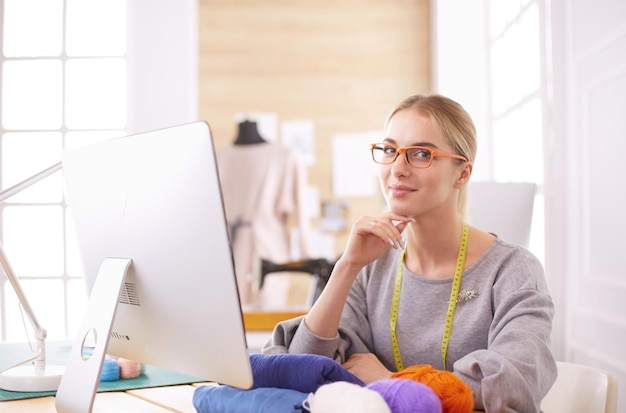 Fashion designer woman working in studio sitting at thhe desk