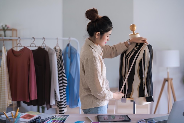 Fashion designer women use measure tape to measuring size and checking details clothes on mannequin