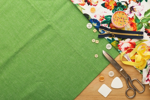 Fashion designer workspace top view. Sewing equipment, ruler, chalk pieces, pins and scissors on cloth squares with copy space