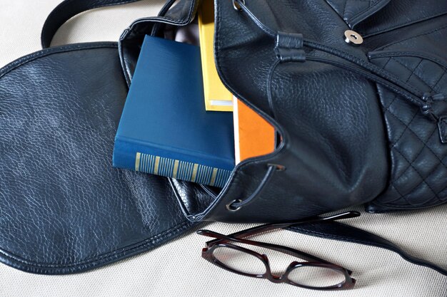 Photo fashion female backpack with books and glasses close up