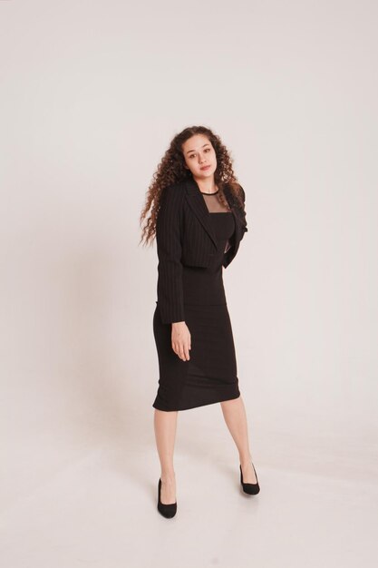 fashion female portrait girl curly girl with black hair in a strict business suit on a white