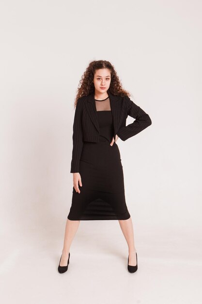 fashion female portrait girl curly girl with black hair in a strict business suit on a white