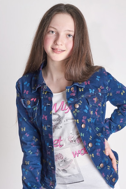 Fashion fun girl in jeans posing on a white background. Model school for children.