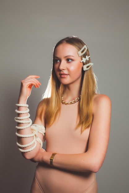 Fashion girl with rope strap on her hand at grey background