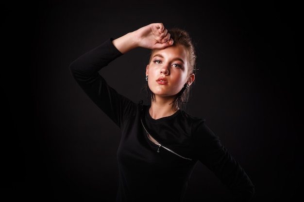 Fashion glamorous portrait of a girl in black dress on dark background Elegant hairstyle bright makeup and lip color