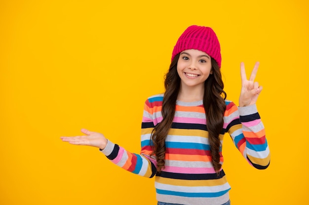 Fashion happy young woman in knitted hat and sweater having fun\
over colorful blue background happy teenager positive and smiling\
emotions of teen girl