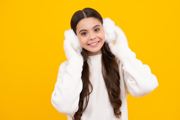 Fashion happy young woman in winter warm earmuff earflaps and sweater having fun over colorful blue background Happy face positive and smiling emotions of teenager girl