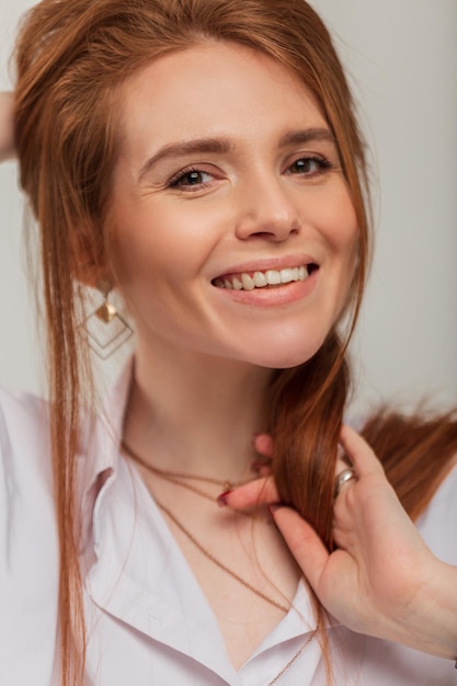 Fashion headshot portrait of beauty redhead happiness woman with cute white smile in white stylish shirt in the studio