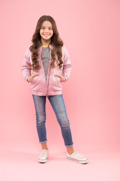 ファッションは彼女の人生です小さなファッションモデルの秋の外観ピンクの背景に居心地の良いファッションの衣装で幸せな女の子子供のための寒い天候のファッションゴージャスで美しい