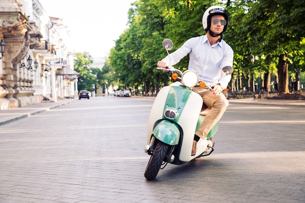 Uomo di moda alla guida di uno scooter