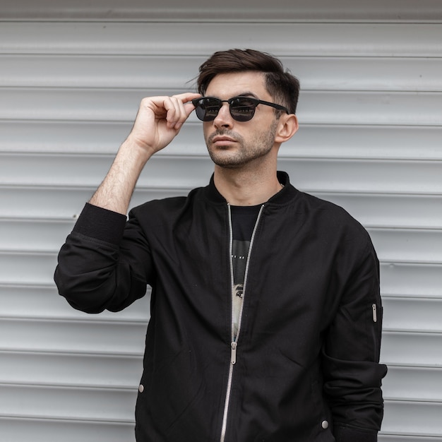 Fashion man with hairstyle in black clothes outdoors 