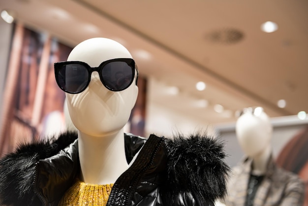 Foto manichini alla moda presso la vetrina del negozio nel centro commerciale vendita di mezza stagione presso il rivenditore di vestiti di stile abbigliamento firmato di sconto visualizzato in negozio o boutique