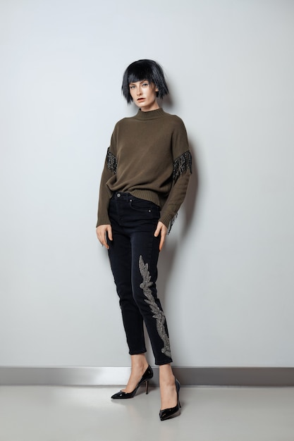 Modella in parrucca nera, pullover con frange e jeans con strass