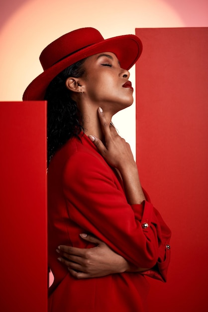 Modella e donna di colore in studio per abiti creativi e posa in power suit su sfondo rosso modella ragazza e abbigliamento elegante dal designer con visione estetica classica e sexy