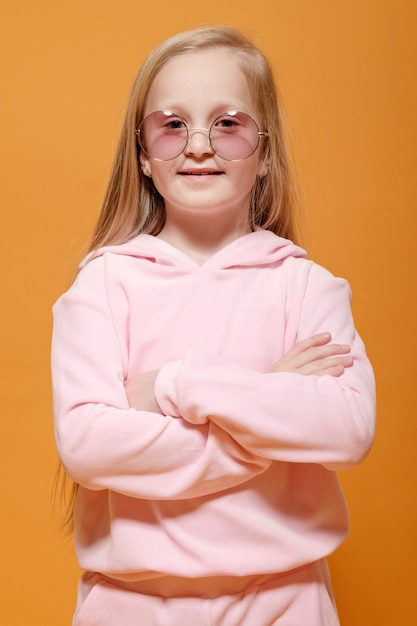 Fashion model blonde girl with glasses in pink clothes on yellow background