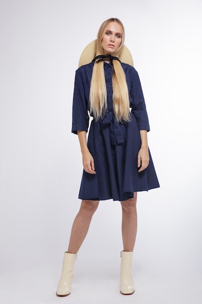 Fashion model in blue dress hat boots on white background Studio Shot portrait Blonde