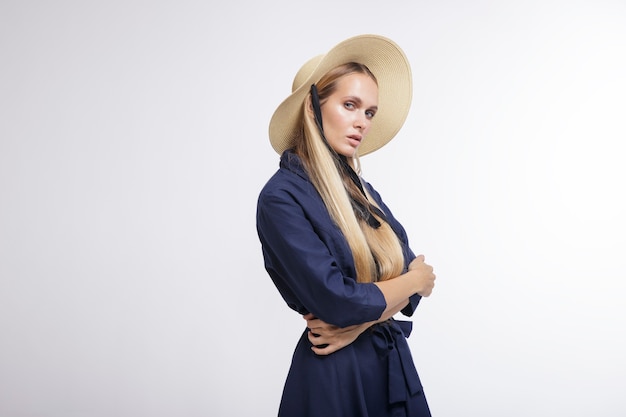 Fashion model in blue dress hat boots on white background Studio Shot portrait Blonde
