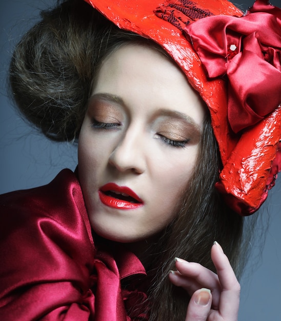 Fashion model in bright red costume and red hat. Studio shot.