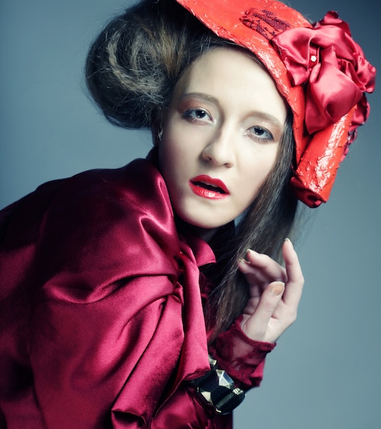 Fashion model in bright red costume and red hat. Studio shot.