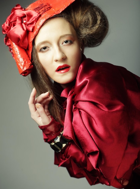 Fashion model in bright red costume and red hat Studio shot