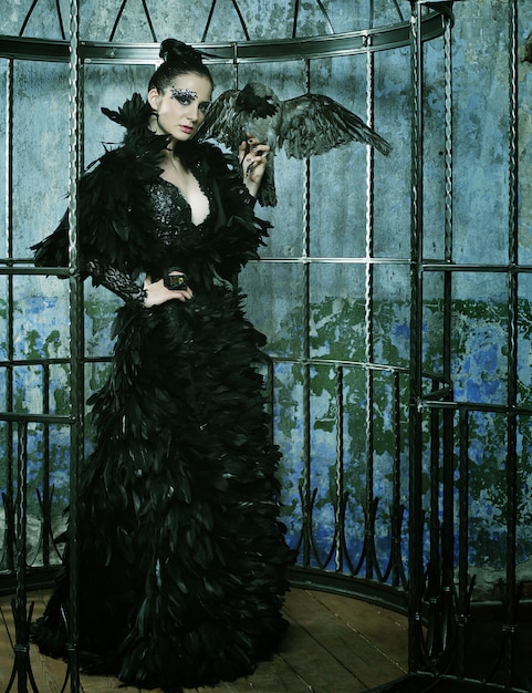 Fashion model in fantasy dress posing in steel cage.