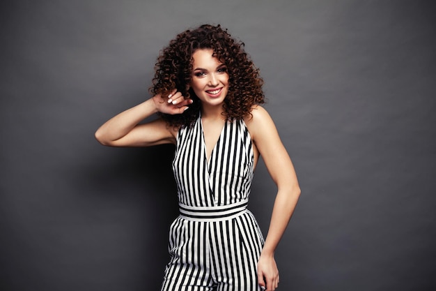 Fashion model meisje geïsoleerd over grijze achtergrond schoonheid stijlvolle brunette vrouw poseren in modieuze kleding in studio casual stijl met schoonheidsaccessoires high fashion stedelijke stijl