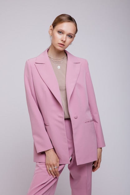 Fashion model in pink oversized suit jacket pants posing over white background Studio Shot