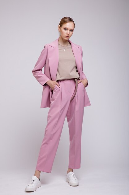 Fashion model in pink oversized suit jacket pants sneakers white background Studio Shot