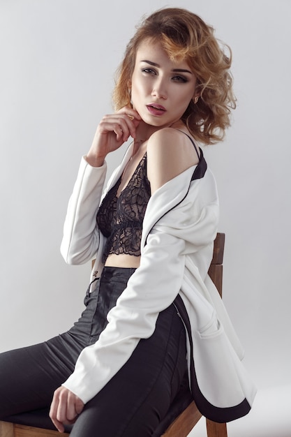 Fashion model posing in white jacket on gray background