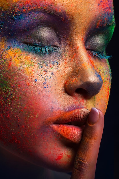 Foto modello di moda con trucco colorato mostra segno di silenzio. bella donna con trucco creativo splash, raccolto
