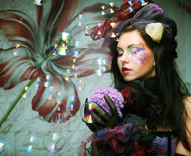 Fashion model with creative makeup blowing soap bubbles