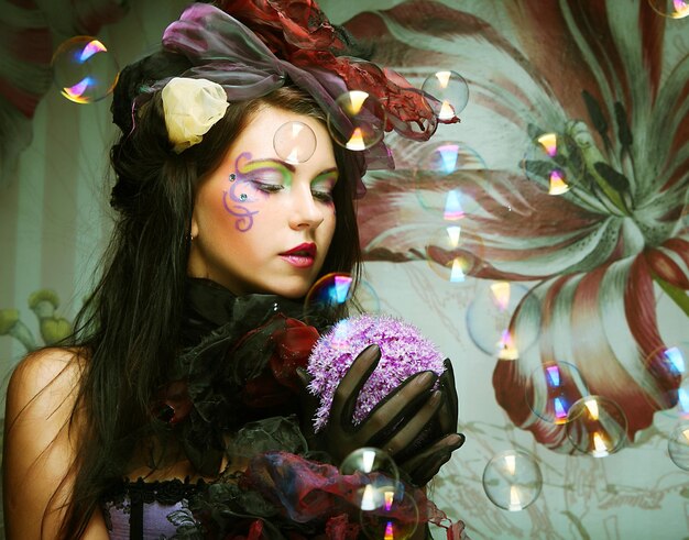 Fashion model with creative makeup blowing soap bubbles